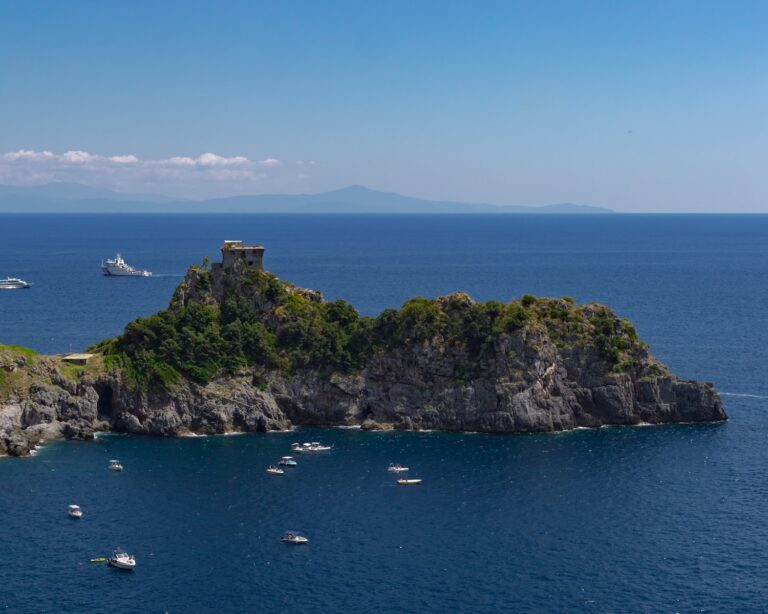 una isla rocosa con barcos con Isola Bella al fondo